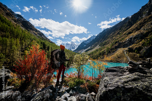 a tourist girl walks with a backpack along the shore of the mountain lake Shavlinskoye in autumn photo