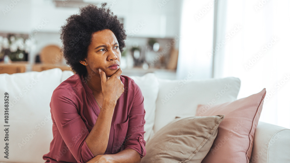 Thoughtful Woman Sitting on a Sofa in a Cozy Living Room Thoughtful Woman Sitting on a Sofa in a Cozy Living Room