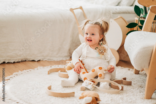 Cute beautiful girl baby sitting on the floor in the children's room and playing in eco soft plush toys