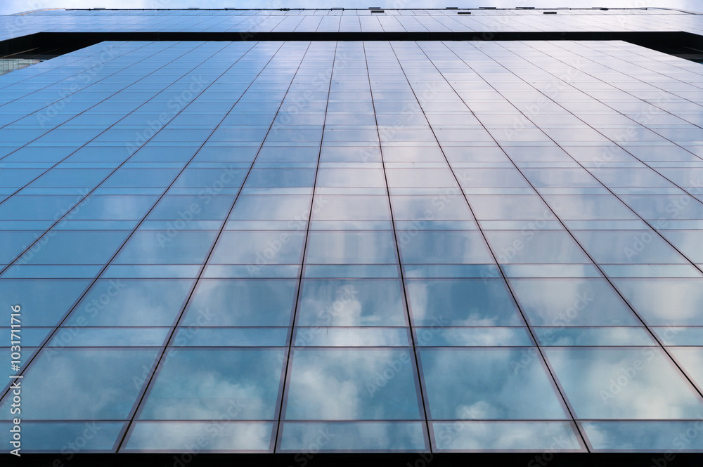 Windows of building at sunset. Reflection of the sky in the window glass. Skyscrapers in business district against blue sky. Looking up high-rise office buildings. Angled view.