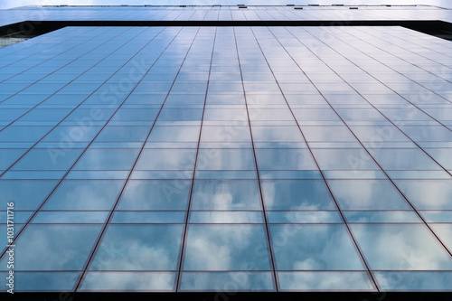 Obraz na płótnie Windows of building at sunset. Reflection of the sky in the window glass. Skyscrapers in business district against blue sky. Looking up high-rise office buildings. Angled view. w salonie
