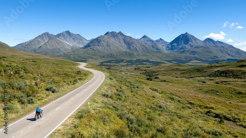 Cyclist Riding Winding Road Through Majestic Mountains