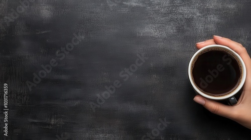 A hand holding a black coffee cup stands out against a textured dark backdrop, capturing a moment of modern coffee indulgence and personal leisure.