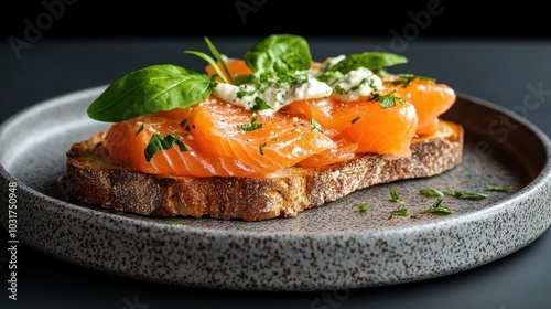 A mouthwatering slice of smoked salmon rests on rustic sourdough bread, garnished with fresh herbs and cream cheese, creating an appetizing culinary masterpiece. photo