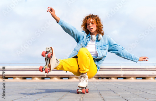 Beautiful red haired young woman with rollerskates having fun outdoors