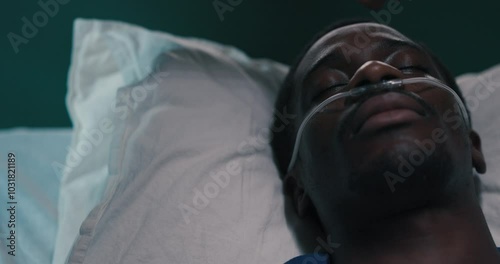 Close up shot of exhausted young African man with oxygen tube in nose African hand strokes his ellbow. photo