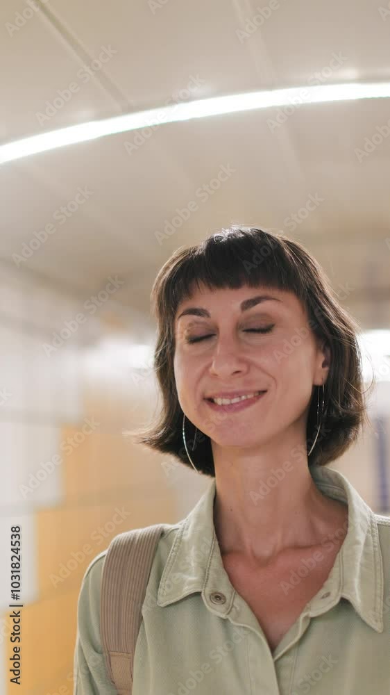 vertical shot. Young girl smiling standing at the subway station. face close-up. Girl waiting for the train. Girl in the subway. vertical shot. Young girl smiling standing at the subway station. face close-up. Girl waiting for the train. Girl in the subway.