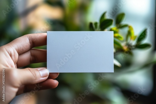 Hand holding a blank business card with a blurred background.