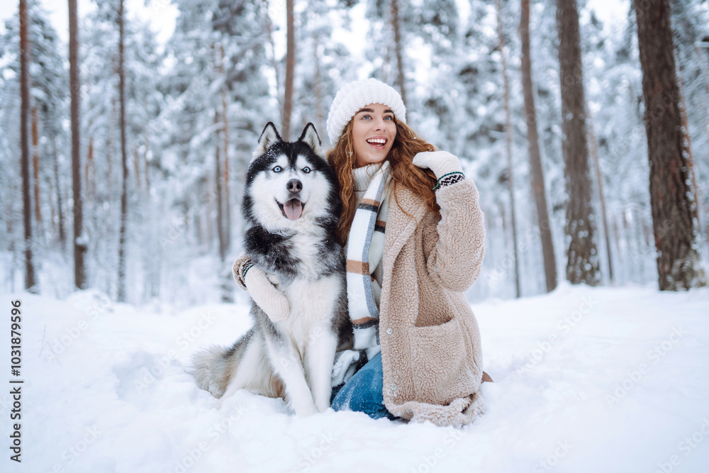 Cheerful woman in the snow playing with a husky dog. Friendship. Domestic dog concept.