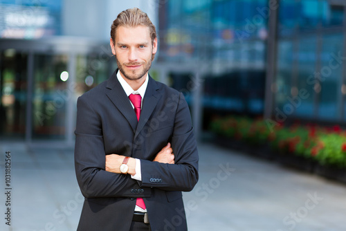 Young caucasian male executive with crossed arms outside corpora photo