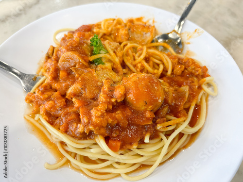 A plate of spaghetti with a thick, red tomato sauce is served with two forks. photo