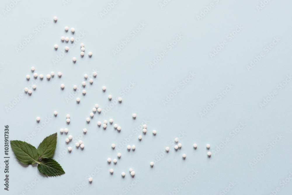 Homeopathic globules and mint leaves on blue background. Alternative medicine herbs, healthcare and pills concept. Top view. Copy space. Flat lay. Homeopathy Homeopathic globules and mint leaves on blue background. Alternative medicine herbs, healthcare and pills concept. Top view. Copy space. Flat lay. Homeopathy