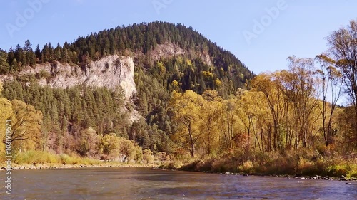 Serene mountain landscape featuring autumn-colored trees as seen from the raft navigated by the local keelman along Dunajec river gorge, Pieniny, Poland  photo