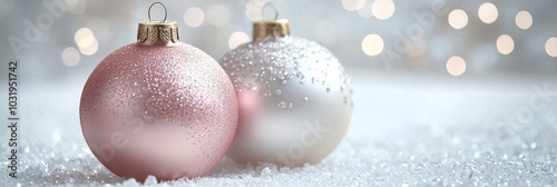 Two sparkling Christmas ornaments on a soft glittering surface with a blurred...