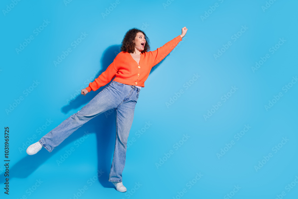 Photo portrait of young latin funny lady with curly hairstyle raised fist up motivated be the best isolated on blue color background Photo portrait of young latin funny lady with curly hairstyle raised fist up motivated be the best isolated on blue color background