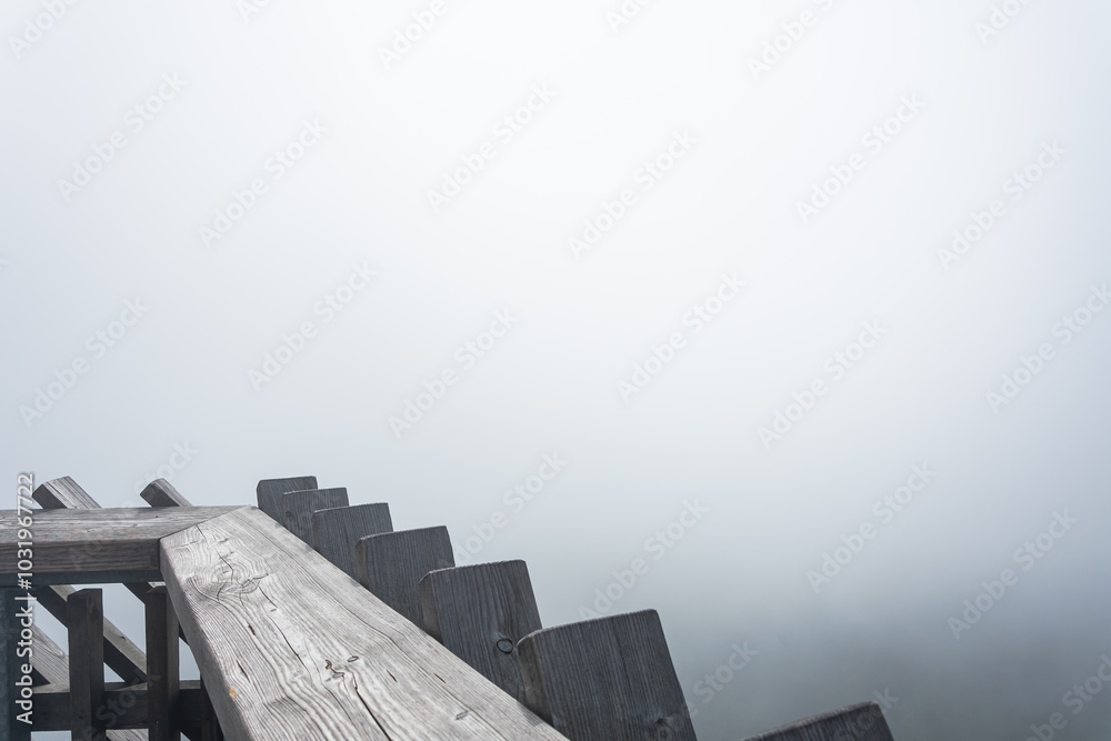 Balustrade on the top of an observation tower in the mountains, thick morning fog in the forest.