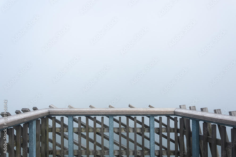 Balustrade on the top of an observation tower in the mountains, thick morning fog in the forest.