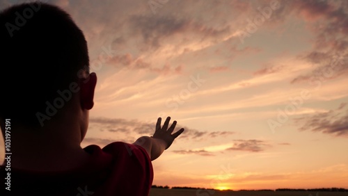 Hand of child boy stretches to beautiful sky, sunset. Childrens dreams hopes, reach out your hands to sky. Childrens prayer. Boy stretches his hand to beautiful sky, dreams in nature. Child is playing