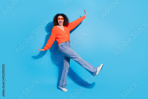 Photo portrait of young latin funny drunk lady with curly hairstyle in orange cardigan dancing night club isolated on blue color background