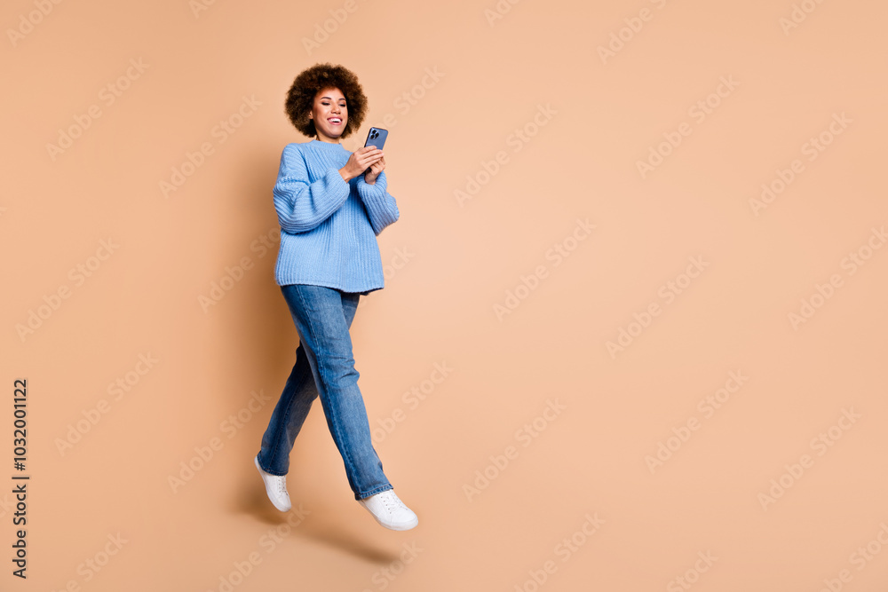Full size photo of nice girl dressed knit sweater jeans flying look at smartphone go empty space isolated on pastel color background Full size photo of nice girl dressed knit sweater jeans flying look at smartphone go empty space isolated on pastel color background