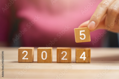 Hand holding wooden cube 2024 to 2025, Merry Christmas and Happy New Year concept.