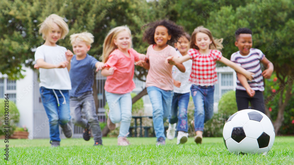 Group Of Children Playing Football With Friends In Park Running Towards Ball In Foreground Group Of Children Playing Football With Friends In Park Running Towards Ball In Foreground