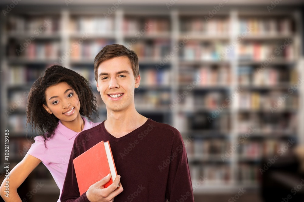 Happy young students in library with books Happy young students in library with books
