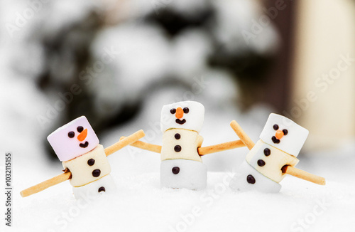 cute marshmallow snowman with face sitting in cacao cup outside on snow, winter cold time.pinecone and branch as decoration.celebrating happy new year and christmas.handmade dessert