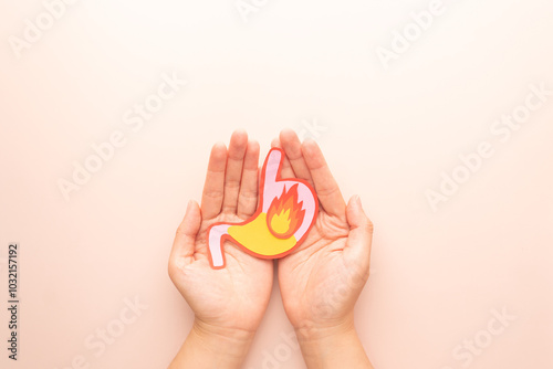 Human stomach burn with acid reflux and fire made from paper on hands. Gastroesophageal reflux disease (GERD) or heartburn symptoms. Gastrointestinal system disease and digestive problems. photo