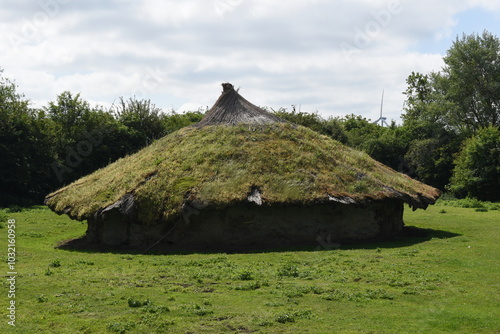 Ancient roundhouse covered in moss on a bright day in the British country.