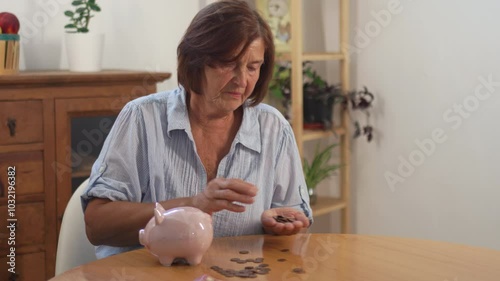 Worried senior woman carefully counting coins from piggy bank on table, her expression reflecting concern as she examines her savings, creating moment of financial crisis 