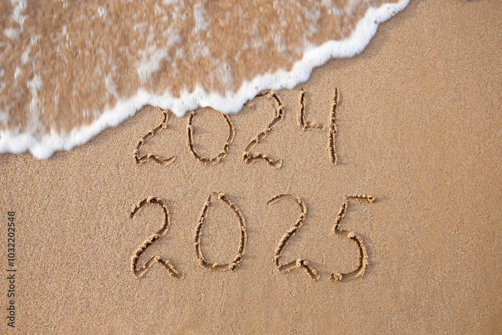 Fototapeta premium 2024, 2025 years written on sandy beach sea. Wave washes away 2024. Happy New Year!