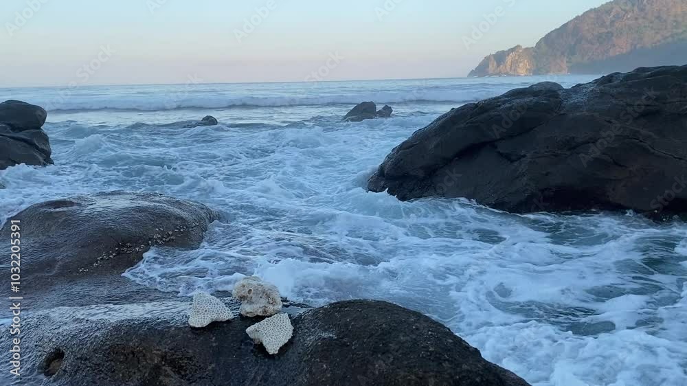The ocean waves crashing on the rocks by the shore The ocean waves crashing on the rocks by the shore