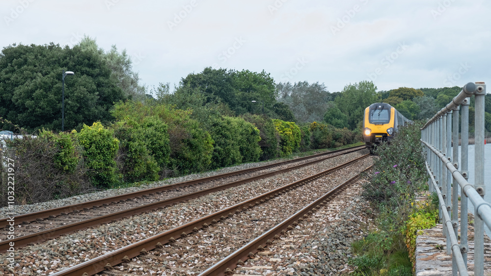 An express train speeding between a verdant trackside and the waters of the river Exe in east Devon UK An express train speeding between a verdant trackside and the waters of the river Exe in east Devon UK