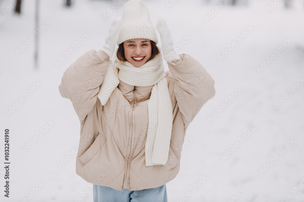 Happy smiling young woman portrait dressed coat scarf hat and mittens enjoys winter weather at snowy winter park