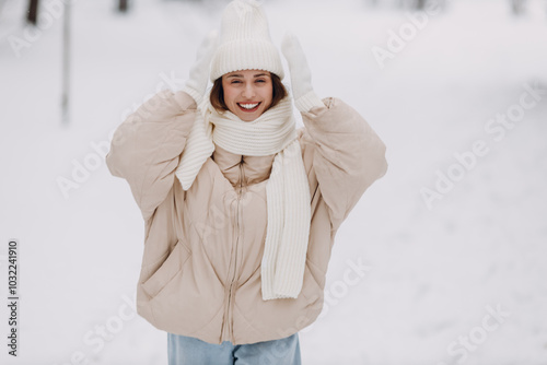 Obraz na płótnie Happy smiling young woman portrait dressed coat scarf hat and mittens enjoys winter weather at snowy winter park w salonie