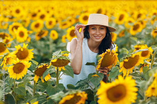 Beautiful young woman in hat on sunflower field.