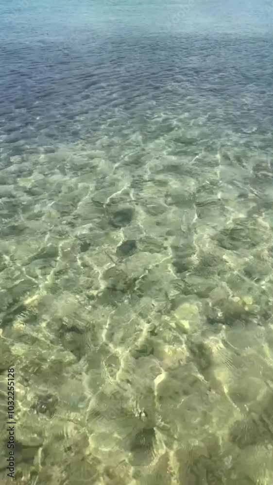 Visible pebbly seabed through incredibly clean and clear undulating Sea Visible pebbly seabed through incredibly clean and clear undulating Sea