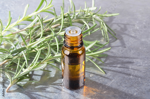 A bottle of rosemary oil, A sprig of fresh evergreen rosemary, on an isolated white background