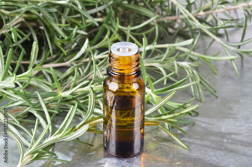 A bottle of rosemary oil, A sprig of fresh evergreen rosemary, on an isolated white background