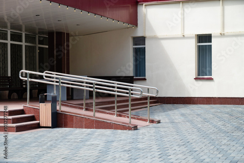 Modern building entrance with wheelchair ramp and stairs.