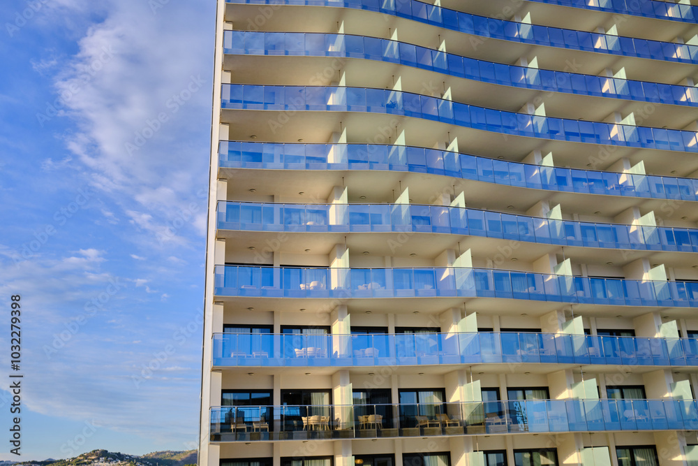 Modern apartment building with balconies and blue sky. Abstract architecture with glass panels. Perfect for modern design projects and presentations. Modern apartment building with balconies and blue sky. Abstract architecture with glass panels. Perfect for modern design projects and presentations.