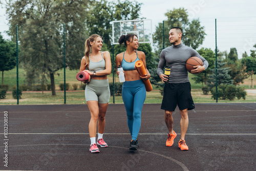 Active, multinational group of friends walking, training together on the street holding sport mat