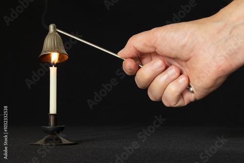 Candle snuffer using to extinguish burning candle photo