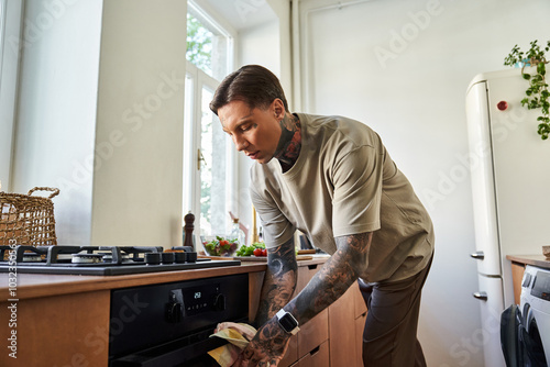 A stylish young man focuses on cooking in his bright home kitchen, surrounded by fresh ingredients.