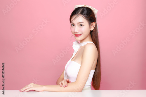 Pretty Asian woman model long hair perfect clear fresh skin smile on isolated pink background. Portrait elegant female beauty blogger make up artist in studio. Skincare, plastic surgery, spa concept.