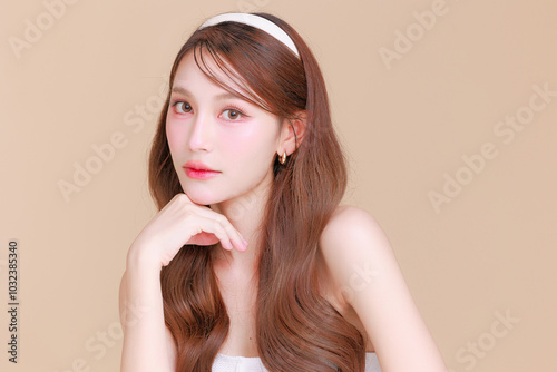 Pretty Asian beauty woman curly long hair with Korean makeup glowing face and healthy facial skin portrait smile on isolated beige background. Cosmetology ,Plastic surgery.