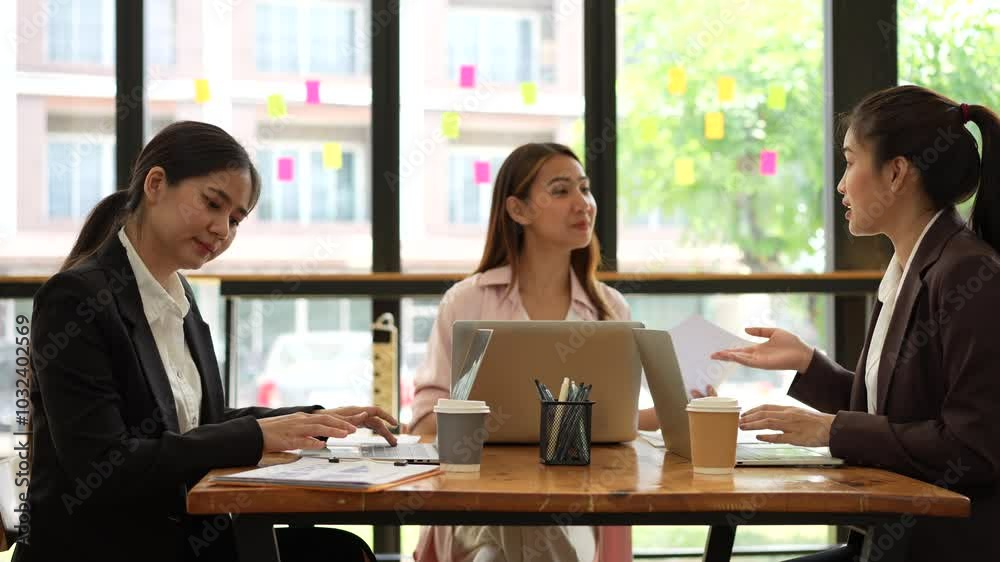 Efficient business meeting with women collaborating over laptop and documents, showcasing teamwork and discussion over coffee in modern office. Efficient business meeting with women collaborating over laptop and documents, showcasing teamwork and discussion over coffee in modern office.