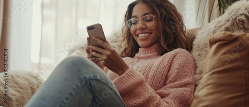 Happy woman using a mobile phone while sitting on a sofa at home