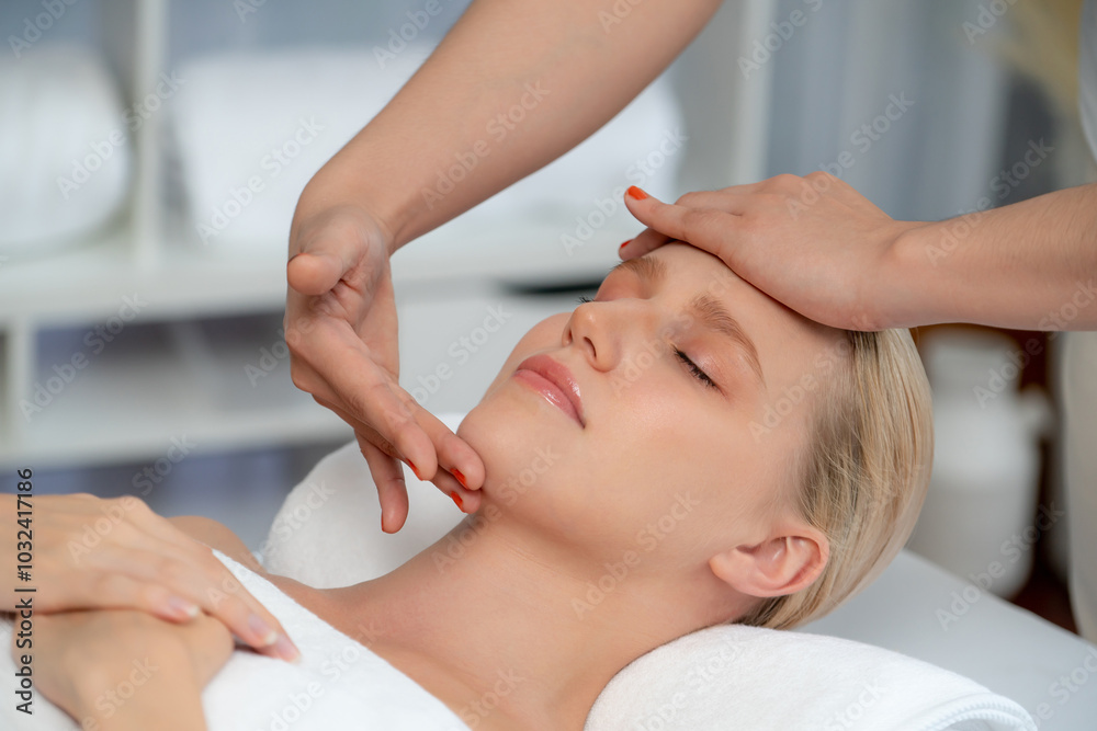 Fototapeta premium Caucasian woman enjoying relaxing anti-stress head massage and pampering facial beauty skin recreation leisure in dayspa modern light ambient at luxury resort or hotel spa salon. Quiescent